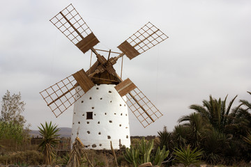 Traditional old white windmill on cloudy day in Fuerteventura, Spain. Wooden blades of medieval architecture building in Canary Islands