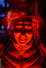 Close-up Of Spooky Red Illuminated Young Man Smiling At Night