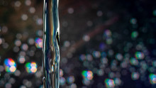 Close-up Of Water Pouring With Illuminated Lights In Background At Night