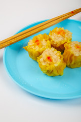 Wall Mural - Siu Mai - Chinese steamed pork dumplings on blue plate isolated on white background.