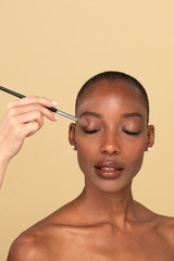 Makeup artist applying eye shadow on a black woman