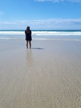 Rear View Of Woman Standing At Beach Against Sky