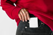 Woman keeping a white card in a pocket of her jeans