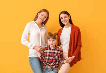 Canvas Print - Happy lesbian couple with little adopted girl on color background