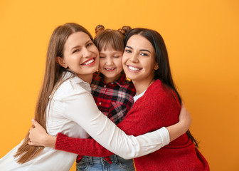 Wall Mural - Happy lesbian couple with little adopted girl on color background