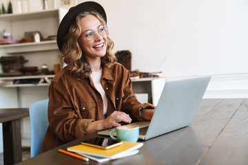 Poster - Image of cheerful woman working with laptop while sitting at table