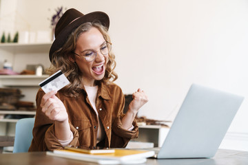 Canvas Print - Image of delighted woman making winner gesture and holding credit card