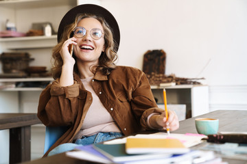 Poster - Image of woman talking on cellphone while studying with exercise books