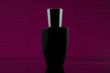 Wall Mural - Bottle of black perfume in pink background. Cosmetic perfume black