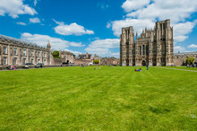 Low Angle View Of Wells Cathedral On Grassy Field Against Cloudy Sky