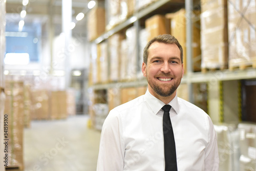 Fotomural portrait friendly businessman/ manager in suit working in the warehouse of a com