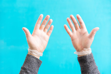 Two male hands with disposable white latex gloves with a light blue background - Conceptual shooting of individual protection from Coronavirus infection