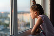 Girl bored at home in quarantine looks out the window