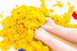 Yellow magic sand in a kids hands on a white background close up. Early sensory education. Preparing for School. Development