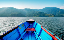 Point Of View Shot From Inside A Blue And Red Row Boat Looking Out On A Mountain Range