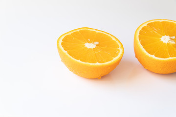 Two halves of fresh orange with drops of water on a white background