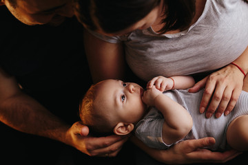 Happy young family with a baby. Parents fun laughing, kissing and hugging their child. 4 months old baby boy