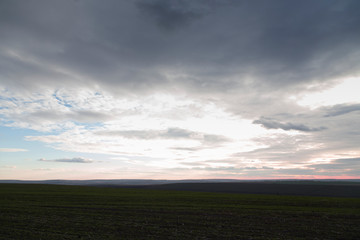 Arable land and the pink sunset with clouds.