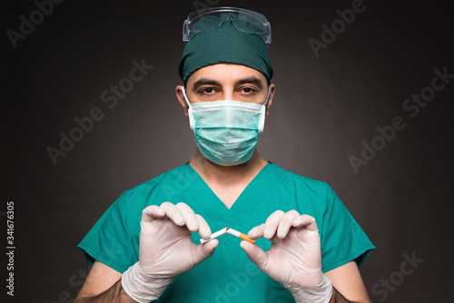 Doctor With Protective Face Mask Breaking Cigarette After COVID-19, Quitting Smoking Concept