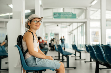 Beautiful young woman is sitting in the waiting room for the arrival of her transport. Hitchhiking in summer.