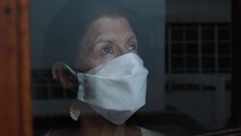 Woman In Quarantine For Covid-19 Looking Out The Window With Eyes Of Hope