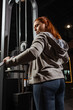© LIGHTFIELD STUDIOS - overweight girl in grey hoodie doing arms extension exercise on fitness machine