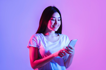 Beautiful smiling asian woman typing on smartphone