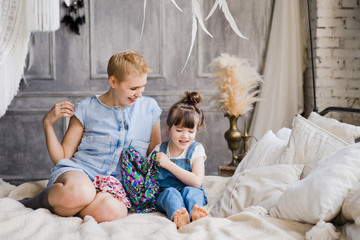 mother and daughter hugging and cuddling in bed. pretty little girl and beautiful woman with short h
