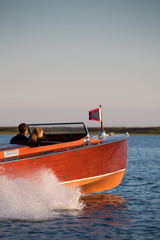 Wall Mural - Young couple riding in a wood speedboat.