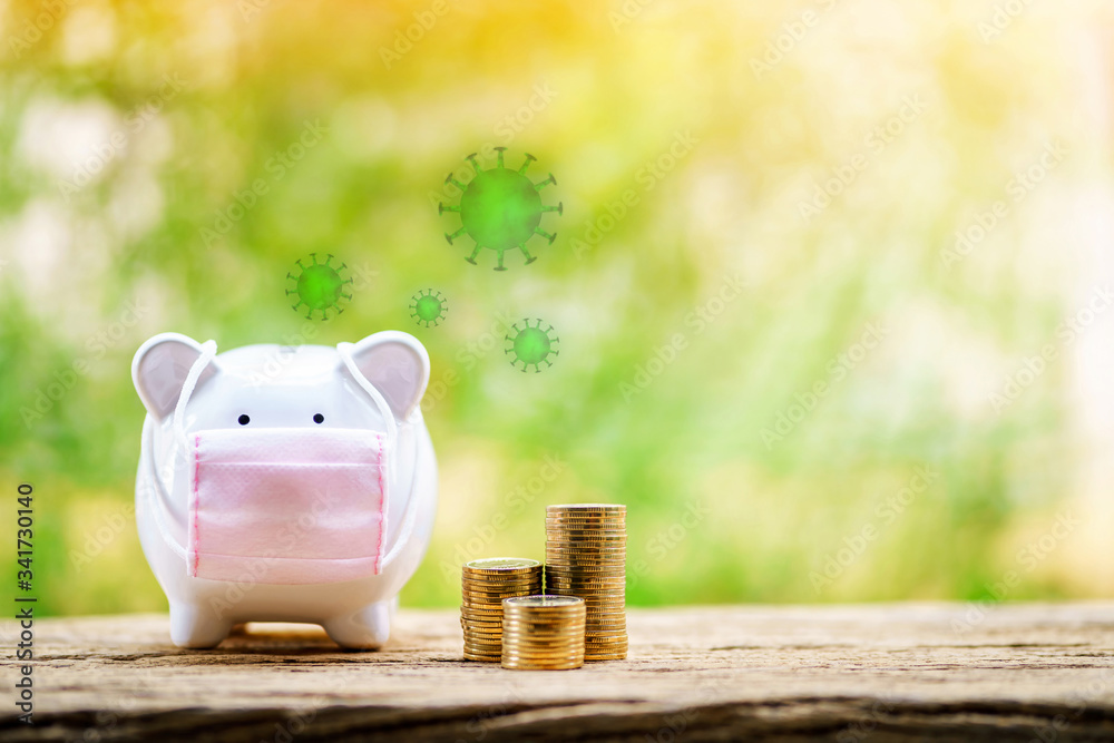 Sick piggy bank wearing surgical mask to prevent viruses and diseases put beside three stack gold coin put on the wood on sunlight in the public park, saving money for buy health insurance concept.