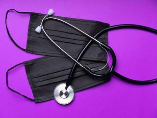 Black stethoscope for doctor diagnostic coronavirus disease, medical tool for health on black background with copy space. Phonendoscope and black mask
on a light purple background. Medical instruments