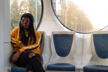 Young black woman sitting alone at public transport during the day, Zagreb, Croatia.