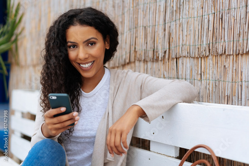 Friendly young African woman relaxing on a bench Poster Mural XXL