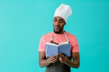 Portrait Of An Young Male Chef  Deciding What To Cook Holding Recipe Book