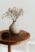 Accessory Composition Detail For Women And Girls. White Flower In A Small Ceramic Vase With Copper Bracelet And Golden Rings On A Wooden Side Table At A White Wall In A Bright Room