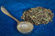 canvas print picture - A pile of loose green tea blend with an ornamental spoon.