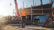 © Gorodenkoff - Back Shot of Worker Contractor Wearing Hard Hat and Safety Vests Walks on Industrial Building Construction Site. In the Background Crane, Skyscraper Concrete Formwork Frames