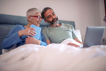 Wall Mural - Senior couple using laptop in bedroom