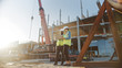 © Gorodenkoff - Two Specialists Inspect Commercial, Industrial Building Construction Site. Real Estate Project with Civil Engineer, Investor Use Laptop. In the Background Crane, Skyscraper Concrete Formwork Frames
