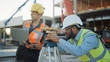 © Gorodenkoff - On the Commercial / Industrial Building Construction Site: Professional Engineer Surveyor Takes Measures with Theodolite, Worker Uses Laptop. In the Background Skyscraper Formwork Frames and Crane