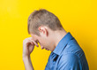© aeroking - Young man in a blue shirt on a yellow background. showing fatigue two hand under head, anger, misunderstanding. gesture. photo shoot.