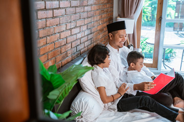 kids and father at home staying during ramadan reading a book