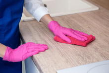 A Girl In Pink Rubber Gloves Washes A Wooden Surface With A Microfiber Cloth.