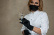 © sun_house_ann - medical worker in black medical gloves and a black medical mask holds a syringe in his hands