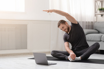 Young man practicing fitness with online training on laptop