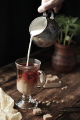 coffee with cream in a rustic style, milk pours into a glass
