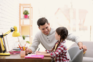 Canvas Print - Man helping his daughter with homework at table indoors