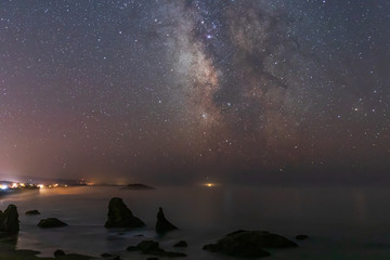Wall Mural - Milky Way Galaxy shining above Bandon Beach as fog comes ashore in Oregon
