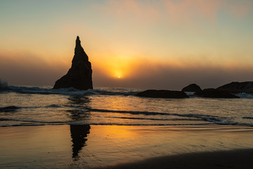 Wall Mural - Sunset shines behind one sea stack along Bandon beach in Oregon
