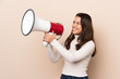 © luismolinero - Young Colombian girl over isolated background shouting through a megaphone